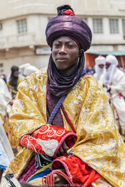 Nigeria, Kano State, Kano. An elegant Hausa man in flowing robes and indigo turban rides his horse during a Durbar celebration.